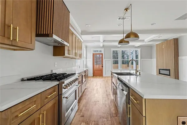 a kitchen with stainless steel appliances granite countertop a sink a stove and a wooden floors