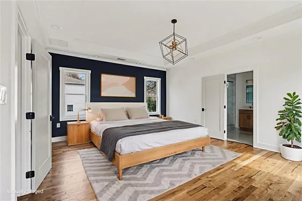 a view of an empty room with chandelier and wooden floor