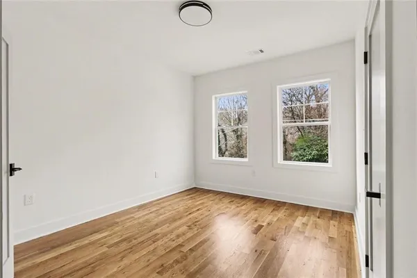 a view of an empty room with wooden floor and closet