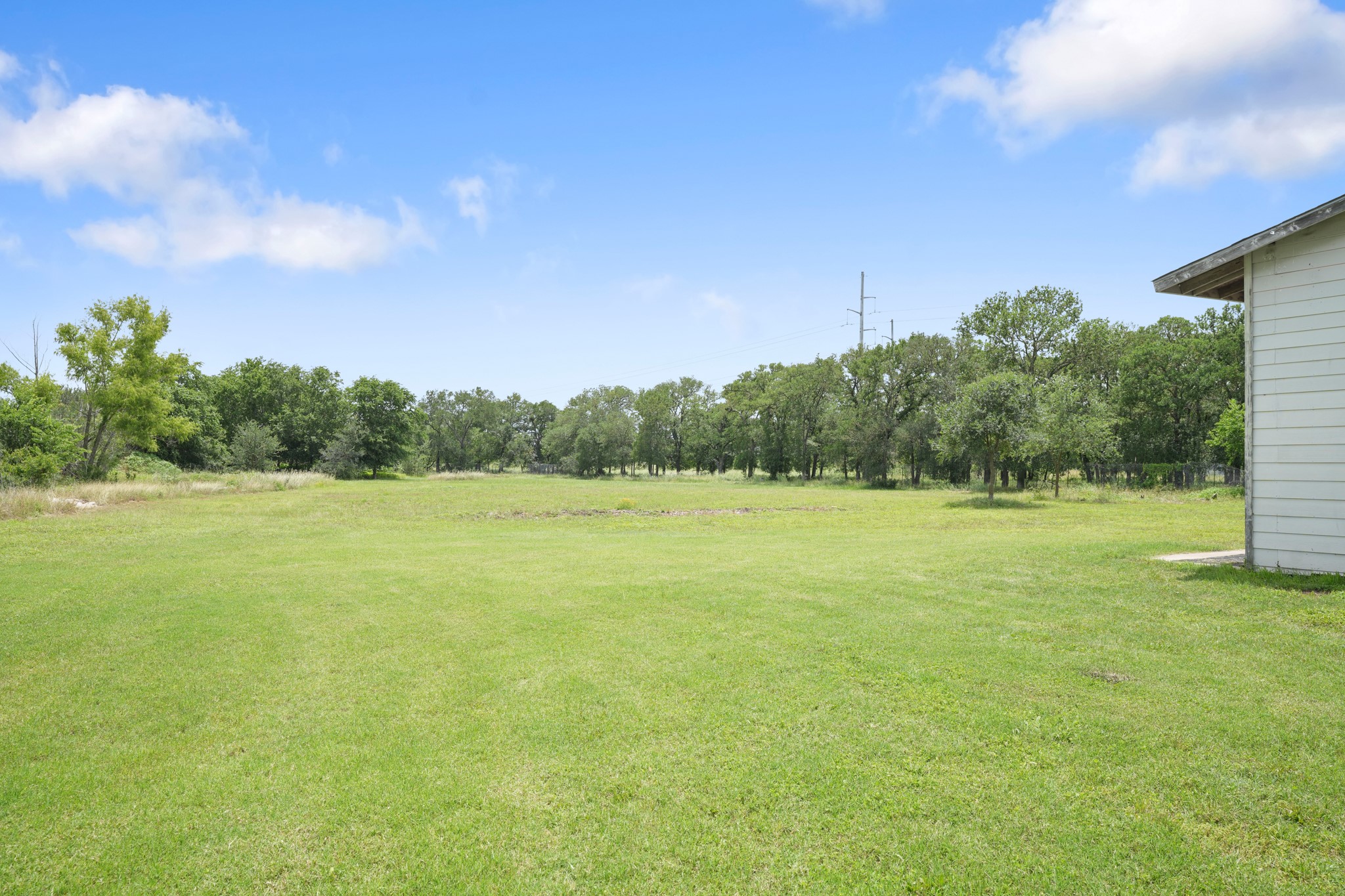 9725 Bock Road Buda, TX 78610 - Photo 30 of 32 A verdant, open field provides ample space for outdoor activities and future expansion.