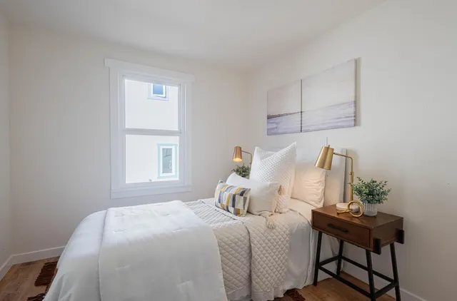 a bedroom with a bed table chair and a window