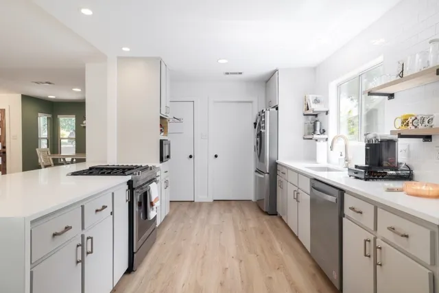 a kitchen with white cabinets and appliances