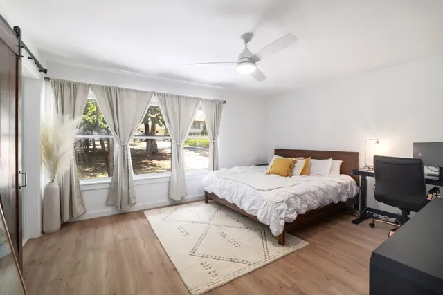 a bedroom with a bed and a large window with wooden floor