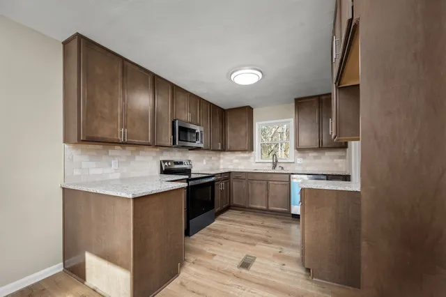 a kitchen with stainless steel appliances granite countertop wooden cabinets a stove top oven a sink and dishwasher