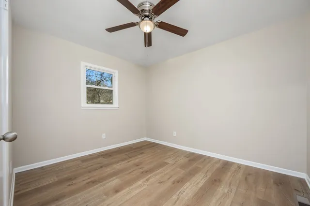 an empty room with a window and a fan