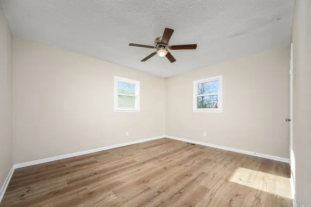 an empty room with wooden floor and windows