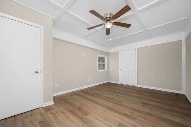an empty room with wooden floor and ceiling fan