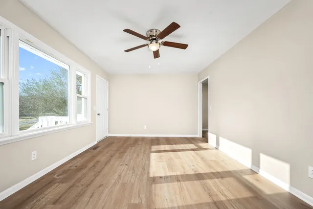 a view of empty room with wooden floor and fan