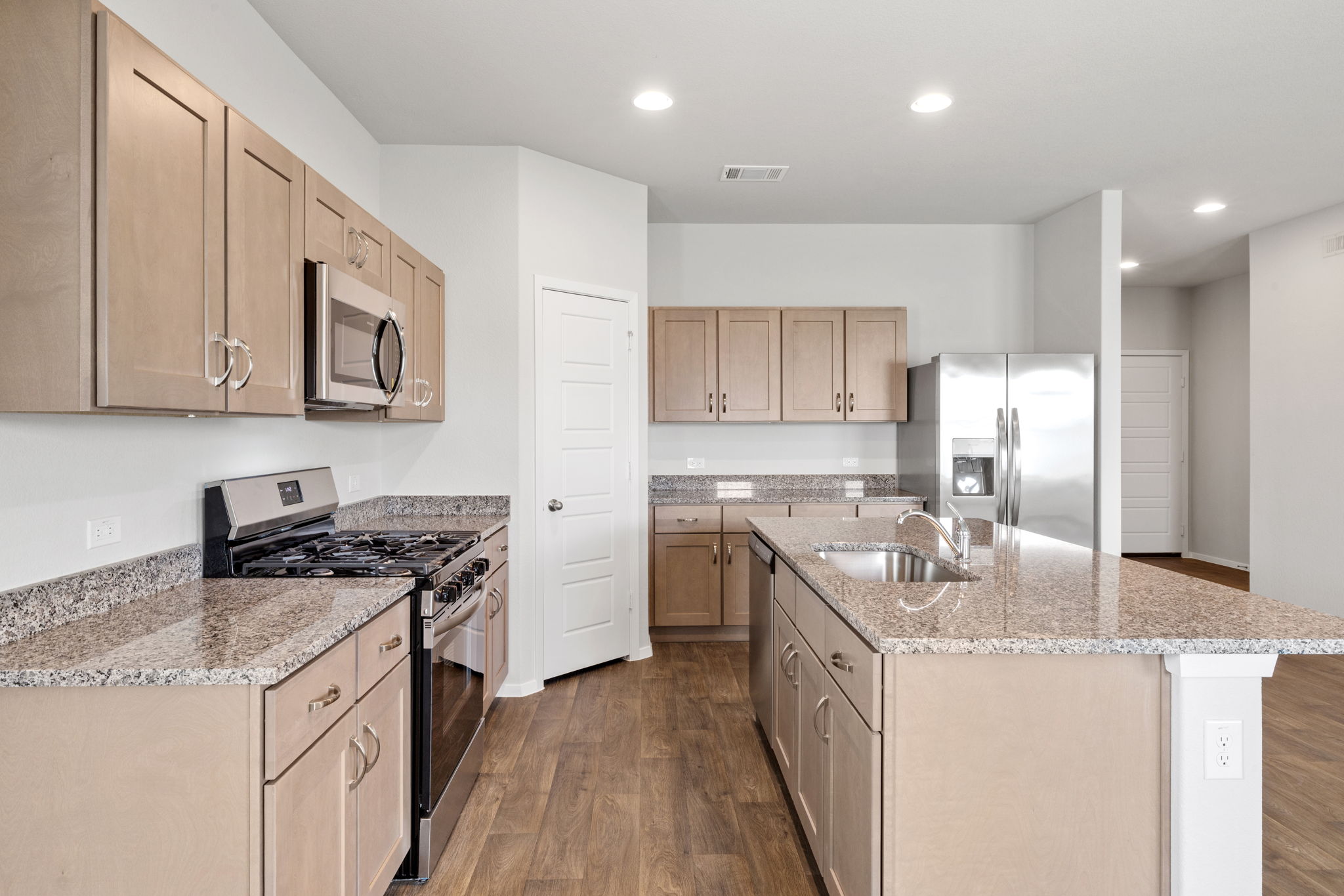 2460 Winding Creek Road Kyle, TX 78640 - Photo 4 of 20 A contemporary kitchen features warm wood cabinetry, granite countertops, and modern stainless steel appliances, creating a highly functional space.