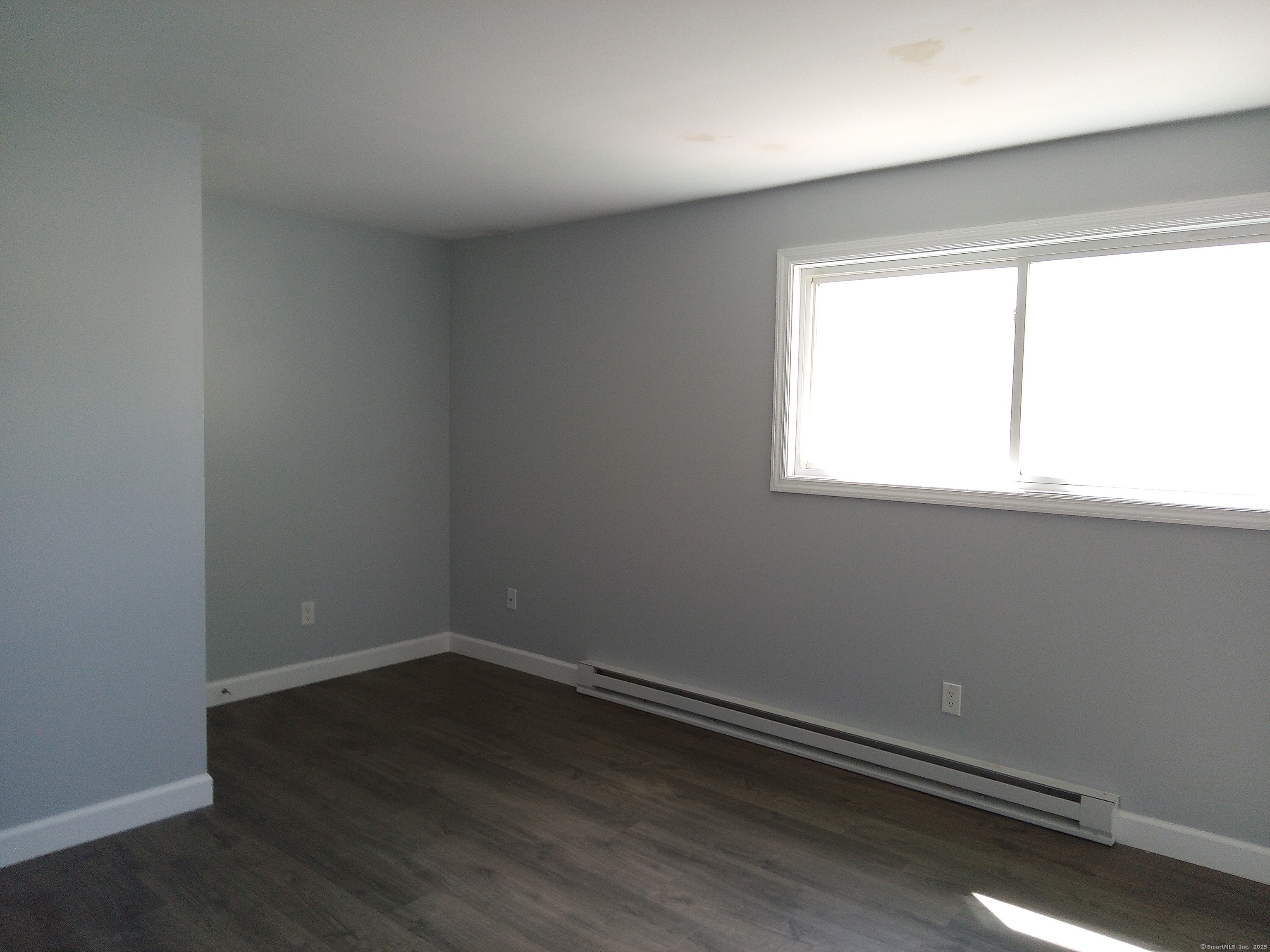 74 Washington Road, Unit 16 Woodbury, CT 06798 - Photo 17 of 25 an empty room with wooden floor and windows