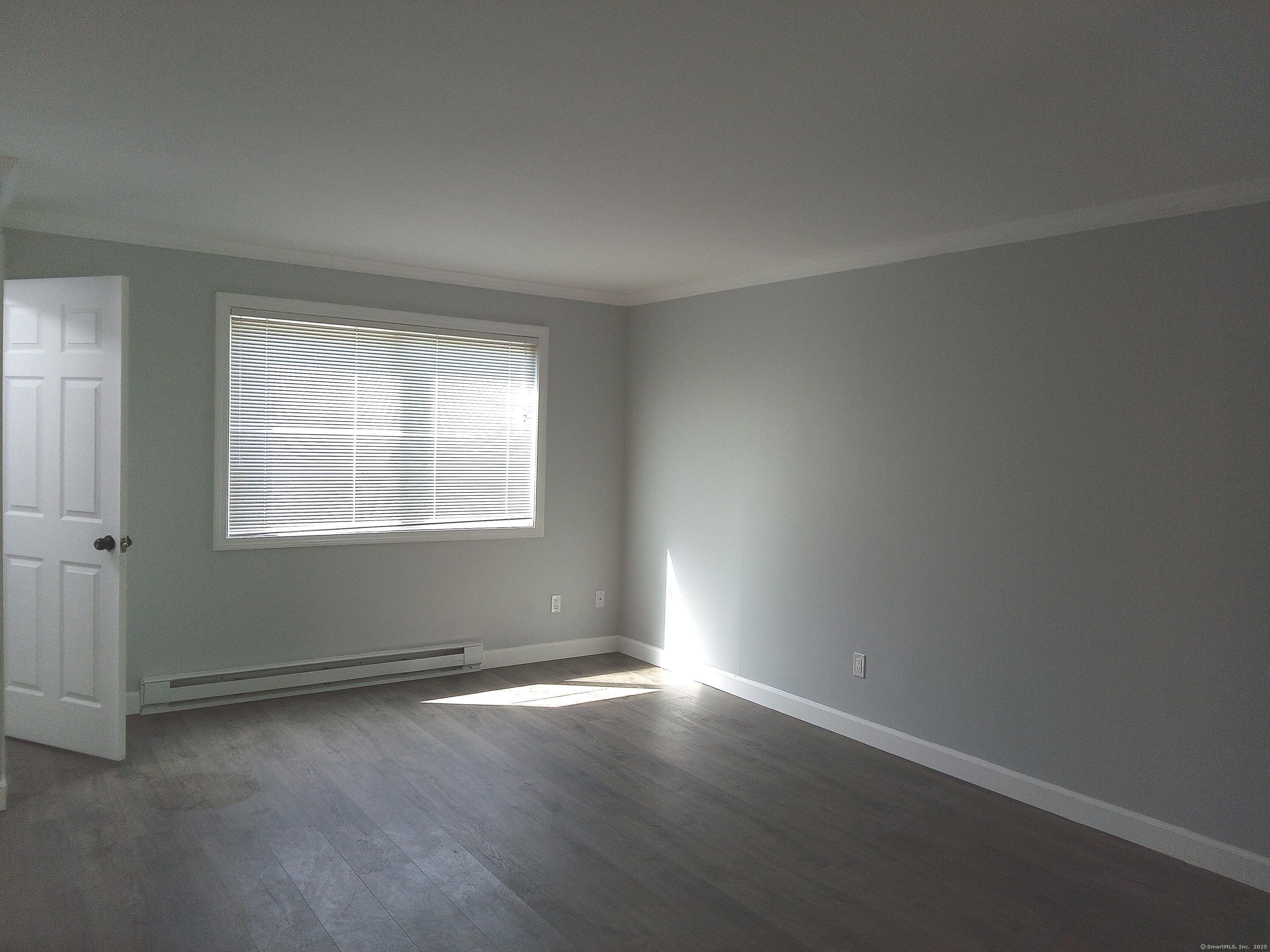 74 Washington Road, Unit 16 Woodbury, CT 06798 - Photo 6 of 25 an empty room with wooden floor and windows