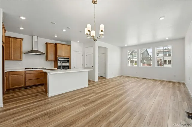 a large kitchen with kitchen island a sink dishwasher a stove and a refrigerator with wooden floor