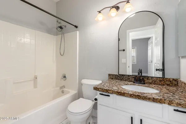 a bathroom with a granite countertop sink a toilet and a mirror