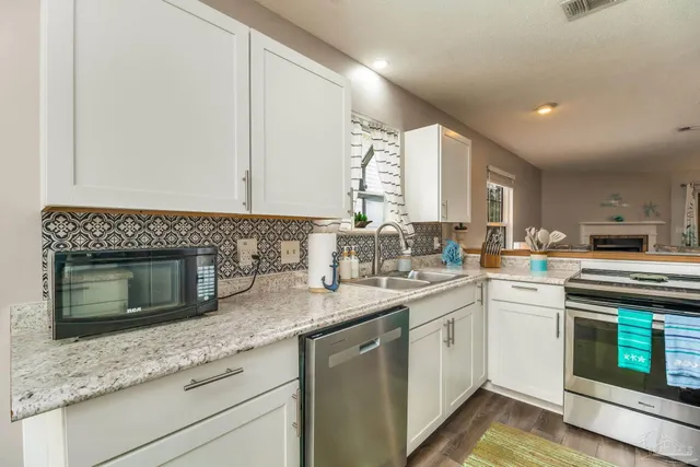 a kitchen with stainless steel appliances granite countertop a stove a sink and a microwave
