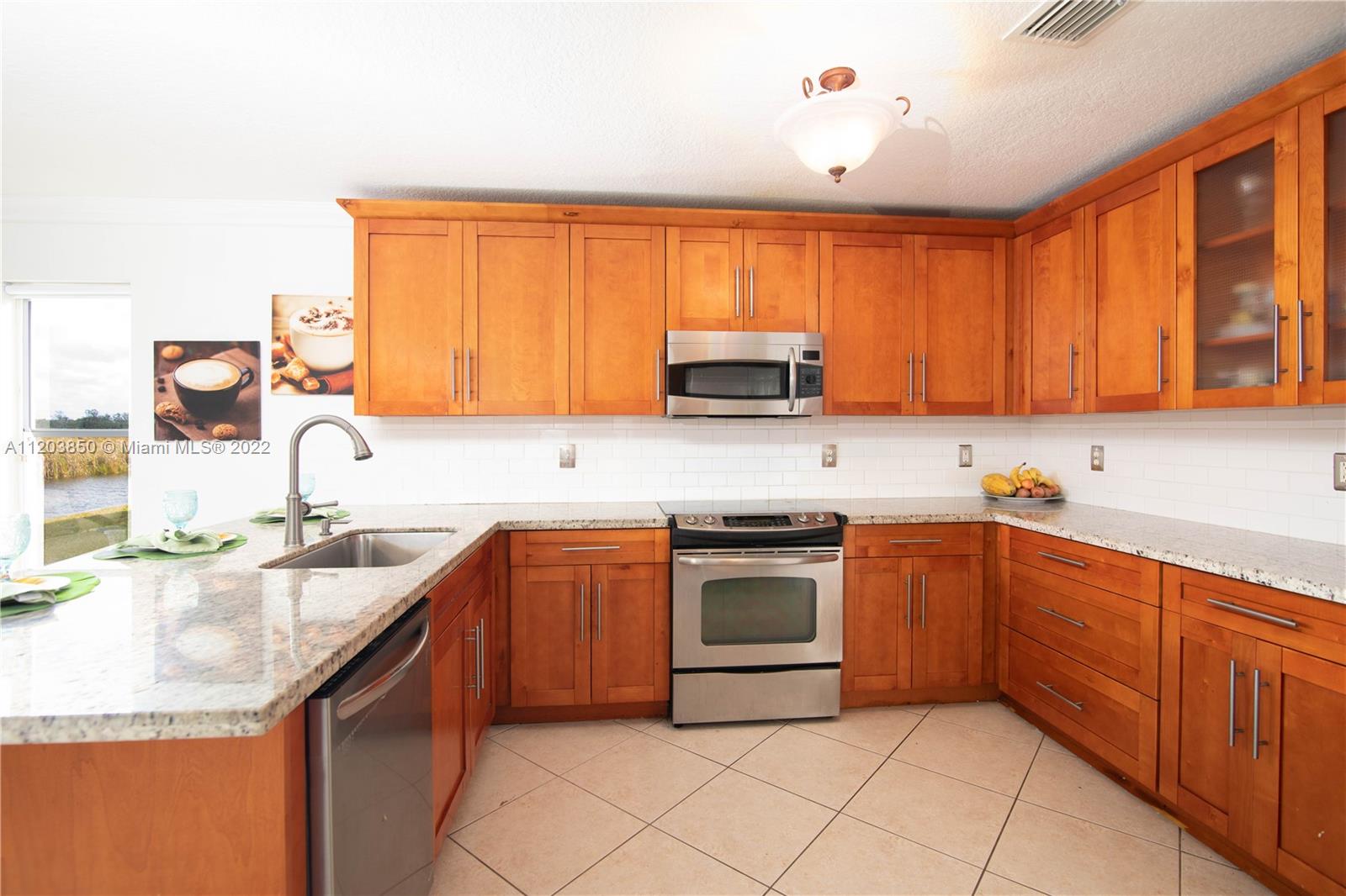 14821 Southwest 20th Street Miramar, FL 33027 - Photo 16 of 50 a kitchen with stainless steel appliances granite countertop a sink stove and microwave