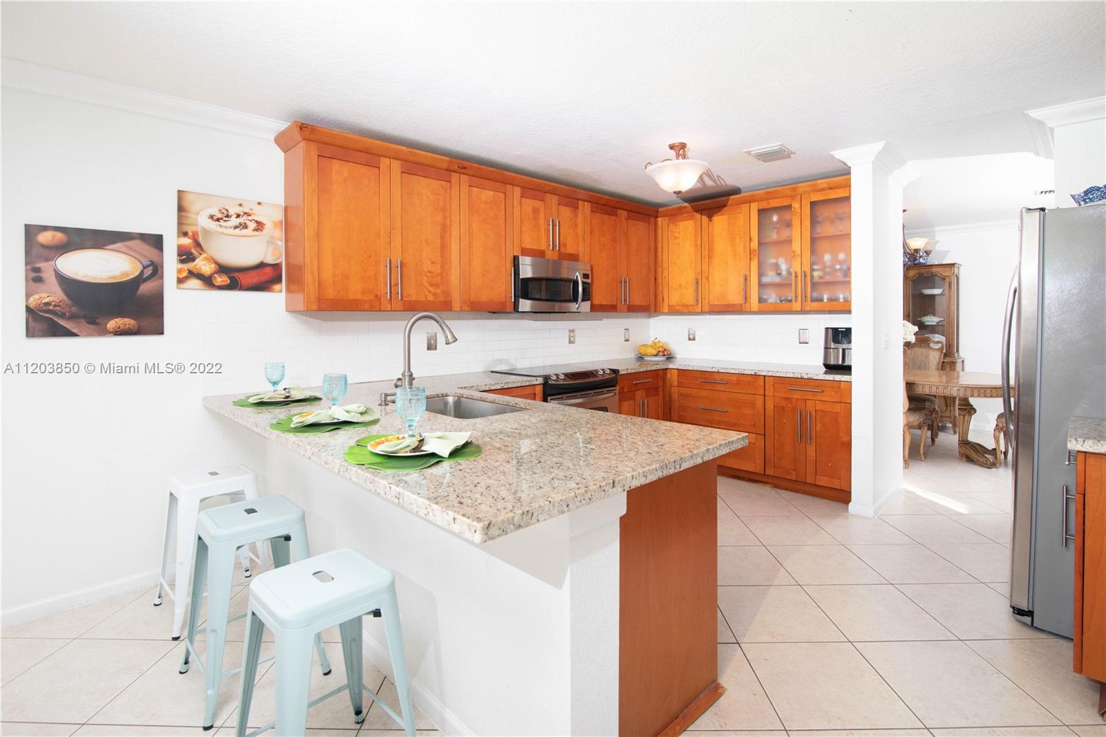 14821 Southwest 20th Street Miramar, FL 33027 - Photo 3 of 50 a kitchen with stainless steel appliances granite countertop a sink and a refrigerator