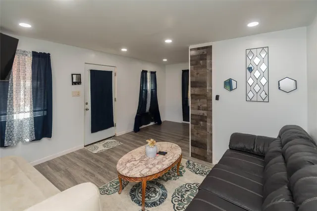 a view of a hallway with wooden floor and a bathroom
