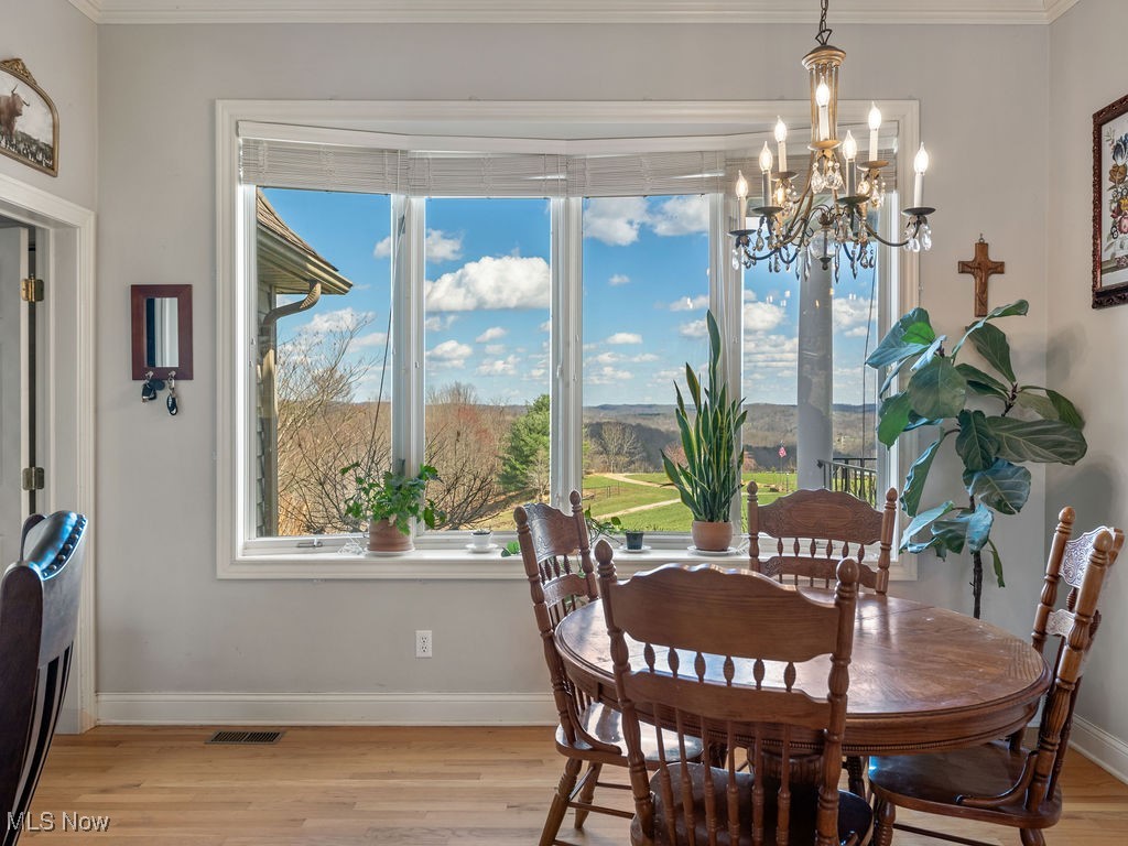 469 Vincent Hill Road Cairo, WV 26337 - Photo 13 of 48 Dining space featuring crown molding, a chandelier, light wood-style flooring, baseboards, and visible vents