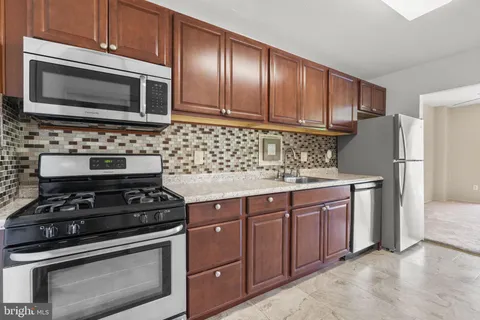 a kitchen with granite countertop wooden cabinets and stainless steel appliances