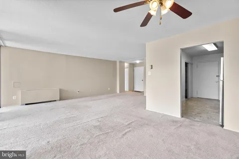 an empty room with chandelier fan and windows