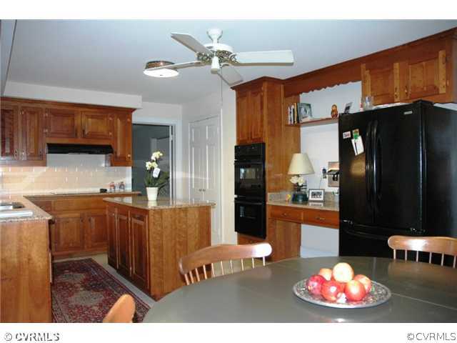 10319 Cherokee Road Richmond, VA 23235 - Photo 8 of 12 a kitchen with stainless steel appliances kitchen island granite countertop a refrigerator dining table and chairs