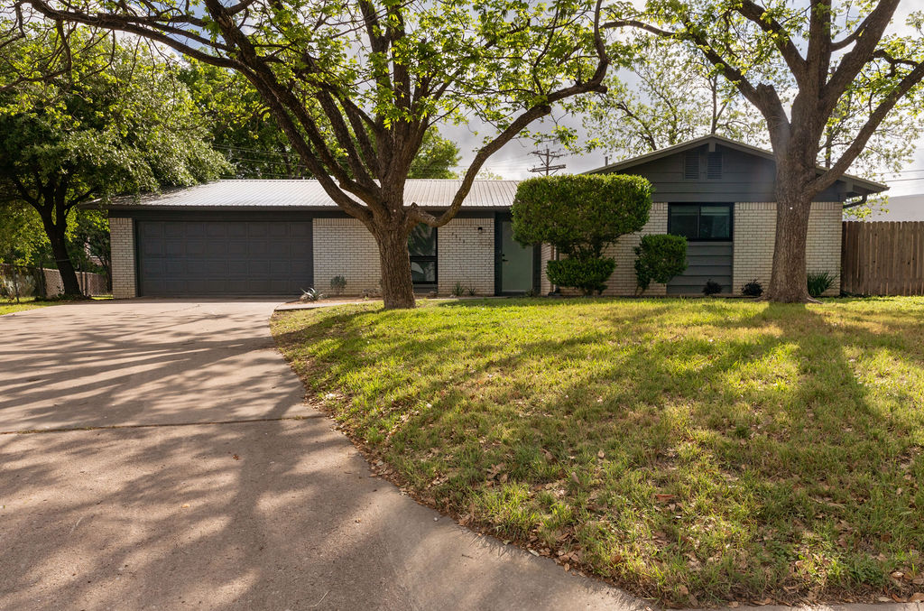 7515 Daugherty Street Austin, TX 78757 - Photo 1 of 1 Ranch-style house with fence, a front lawn, brick siding, a garage, and driveway