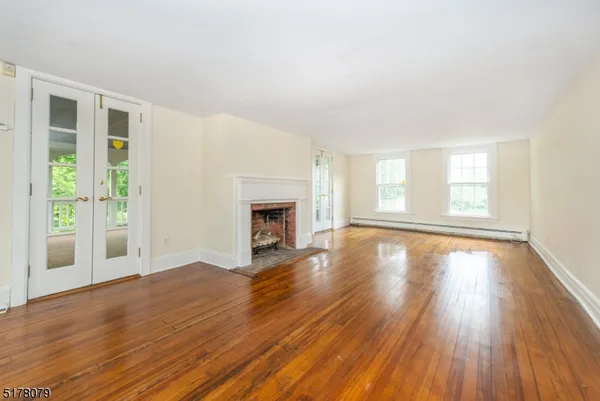 an empty room with wooden floor fireplace and windows