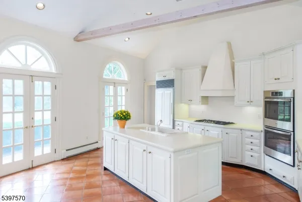 a kitchen with kitchen island granite countertop a stove a sink and white cabinets with wooden floor