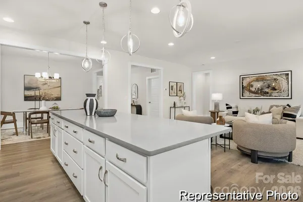 a large white kitchen with a large island oven a stove a dining table and chairs with wooden floor