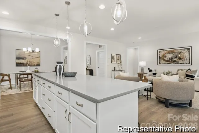 a large white kitchen with a large island oven a stove a dining table and chairs with wooden floor