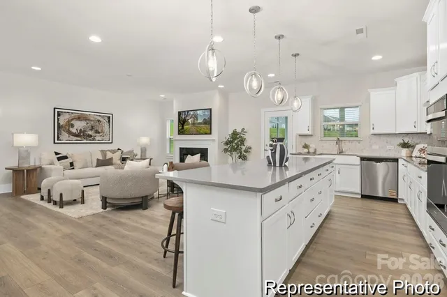 a large white kitchen with a large island oven a stove a chimney a sink and dining table