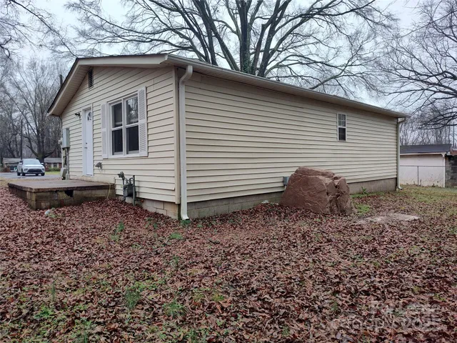 a backyard of a house with wooden fence and large tree