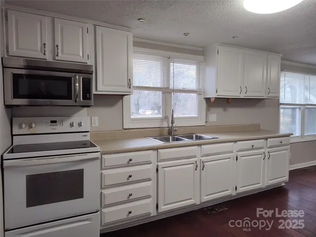 a kitchen with granite countertop cabinets stainless steel appliances and a window