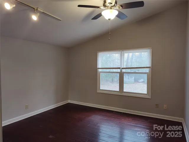 an empty room with wooden floor fan and windows