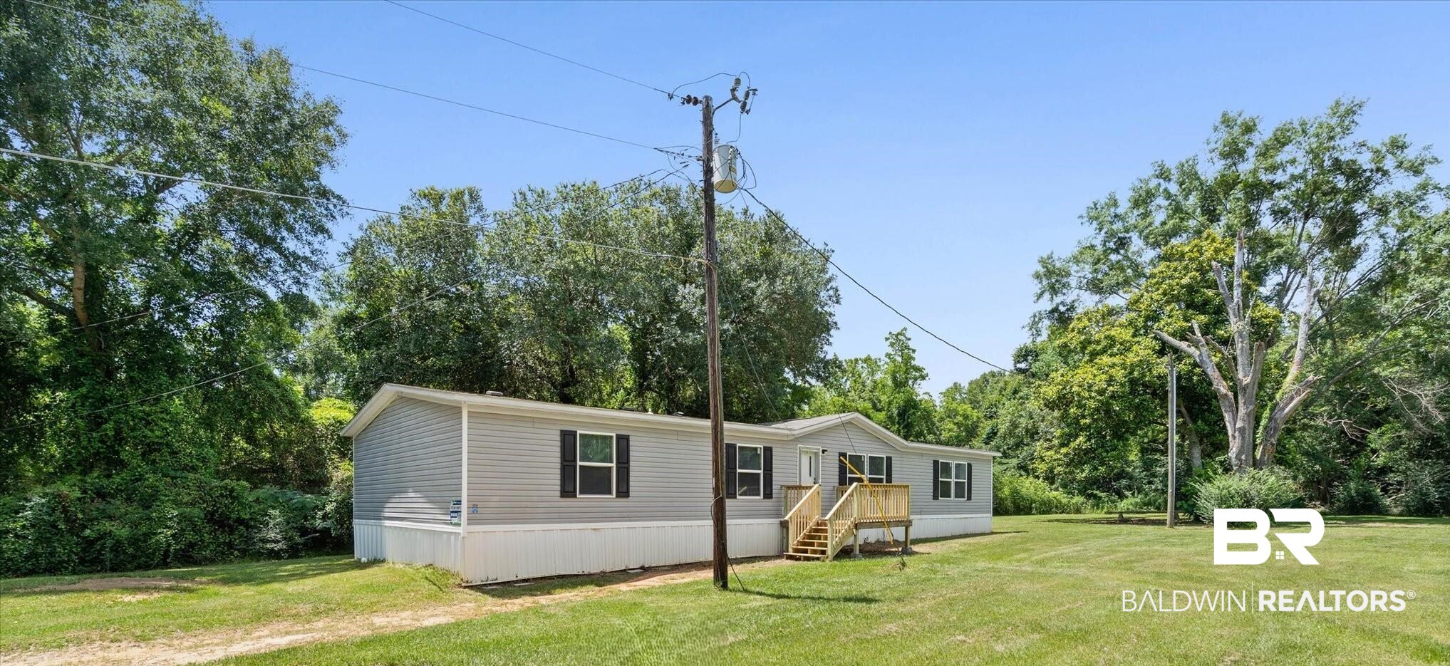 25366 Pollard Road Daphne, AL 36526 - Photo 21 of 22 Manufactured home featuring light gray siding, black shutters, and a wooden front porch with stairs