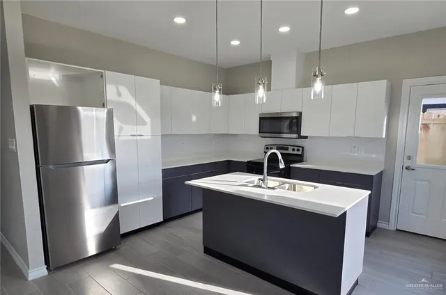 a kitchen with stainless steel appliances granite countertop a sink a stove a refrigerator and a microwave