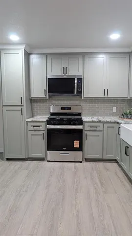 a kitchen with stainless steel appliances a stove top oven a sink and cabinets