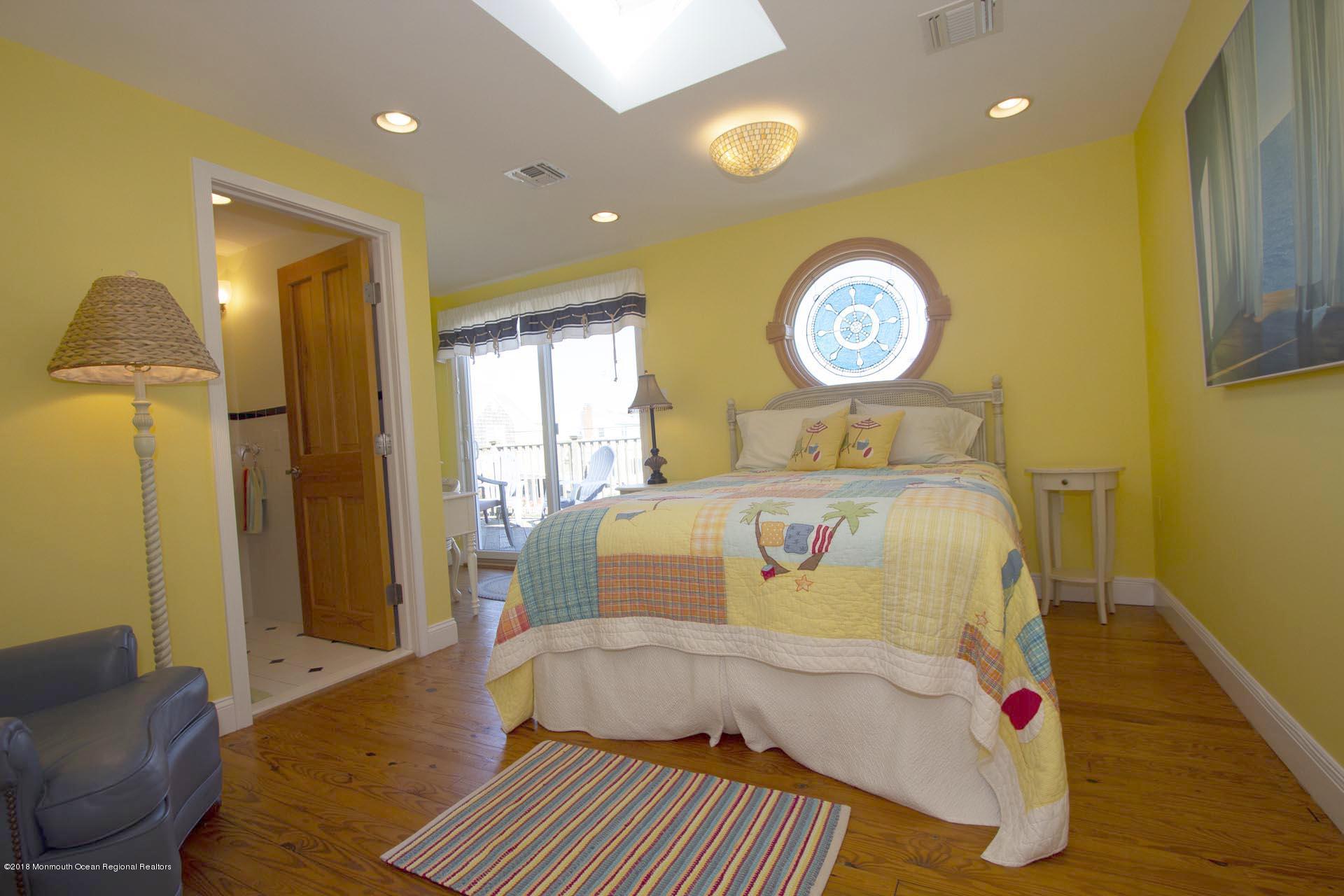 52 Fishermans Road Lavallette, NJ 08735 - Photo 34 of 74 a bedroom with a bed and a lamp on table with wooden floor