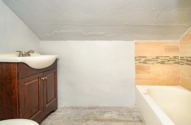 a bathroom with a sink a bathtub and next to a window