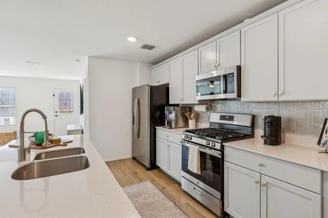 a kitchen with stainless steel appliances granite countertop a stove a sink dishwasher and a refrigerator with wooden floor