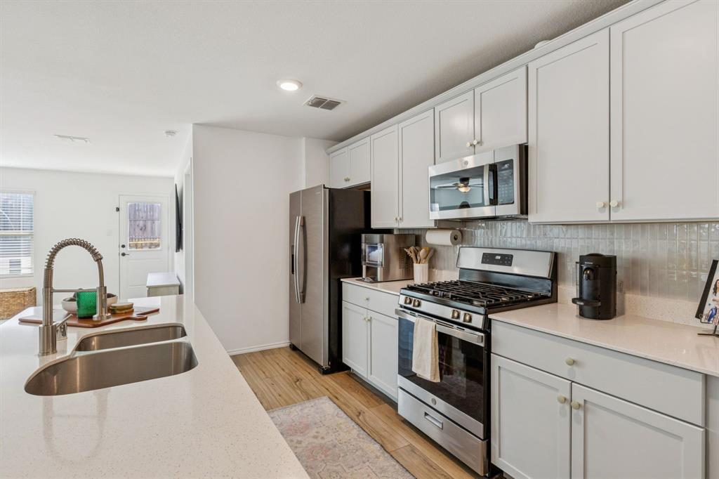 437 Frio Pass Trail Fort Worth, TX 76052 - Photo 8 of 28 a kitchen with stainless steel appliances granite countertop a stove a sink dishwasher and a refrigerator with wooden floor