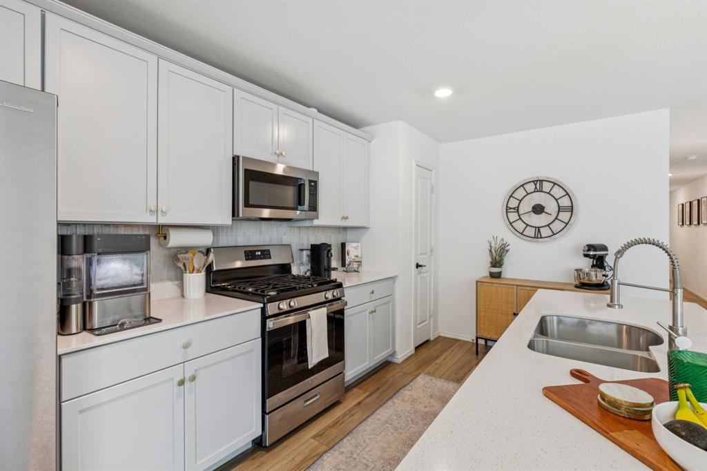 437 Frio Pass Trail Fort Worth, TX 76052 - Photo 9 of 28 a kitchen with stainless steel appliances granite countertop a stove top oven a sink dishwasher and white cabinets with wooden floor