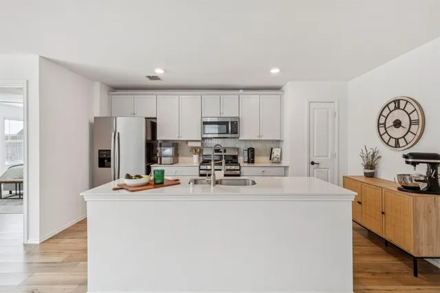a view of kitchen with stainless steel appliances granite countertop a sink a stove a refrigerator with a dining table and chairs