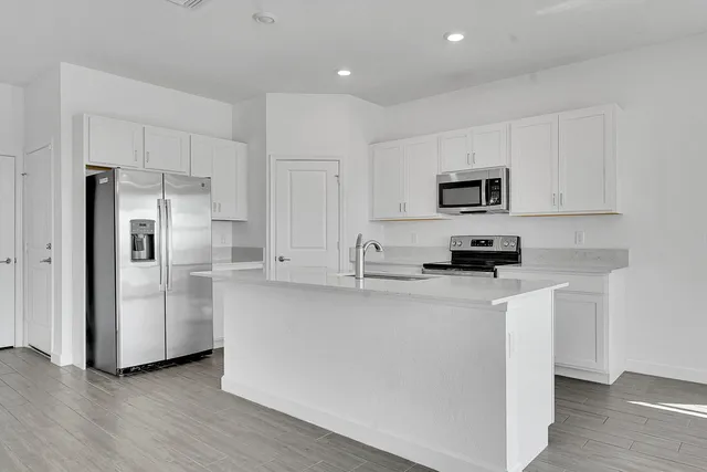 a kitchen with stainless steel appliances granite countertop a sink and stove top oven with wooden floor