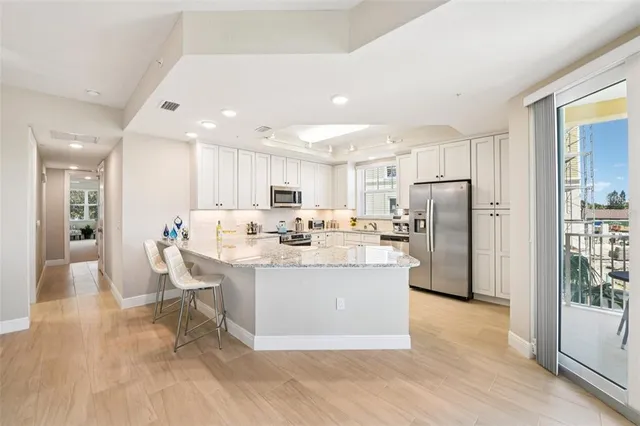 a view of kitchen with stainless steel appliances kitchen island a stove a refrigerator a sink and a view of living room
