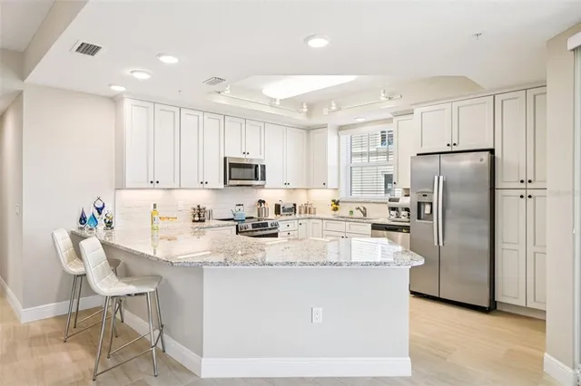 a kitchen with kitchen island white cabinets a refrigerator a stove a oven and white cabinets