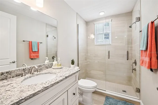 a bathroom with a granite countertop sink a toilet and shower