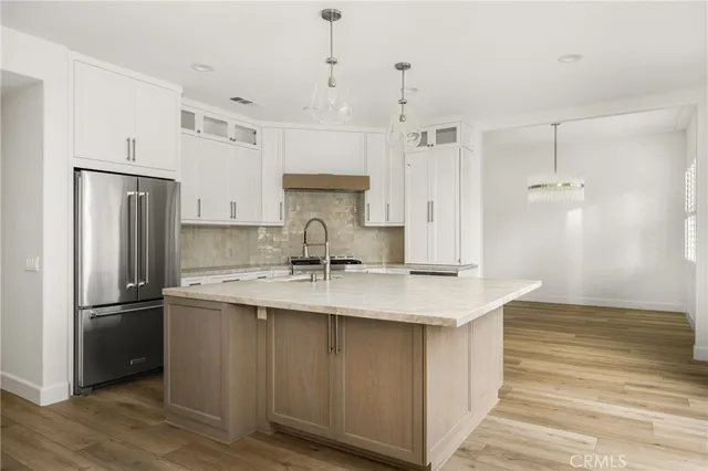 a kitchen with kitchen island white cabinets a refrigerator and a sink