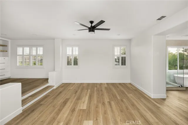 a view of empty room with wooden floor and fan