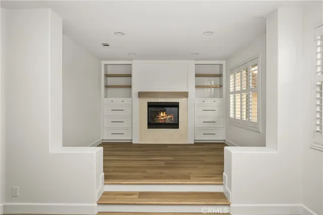 a view of a livingroom with wooden floor and a fireplace